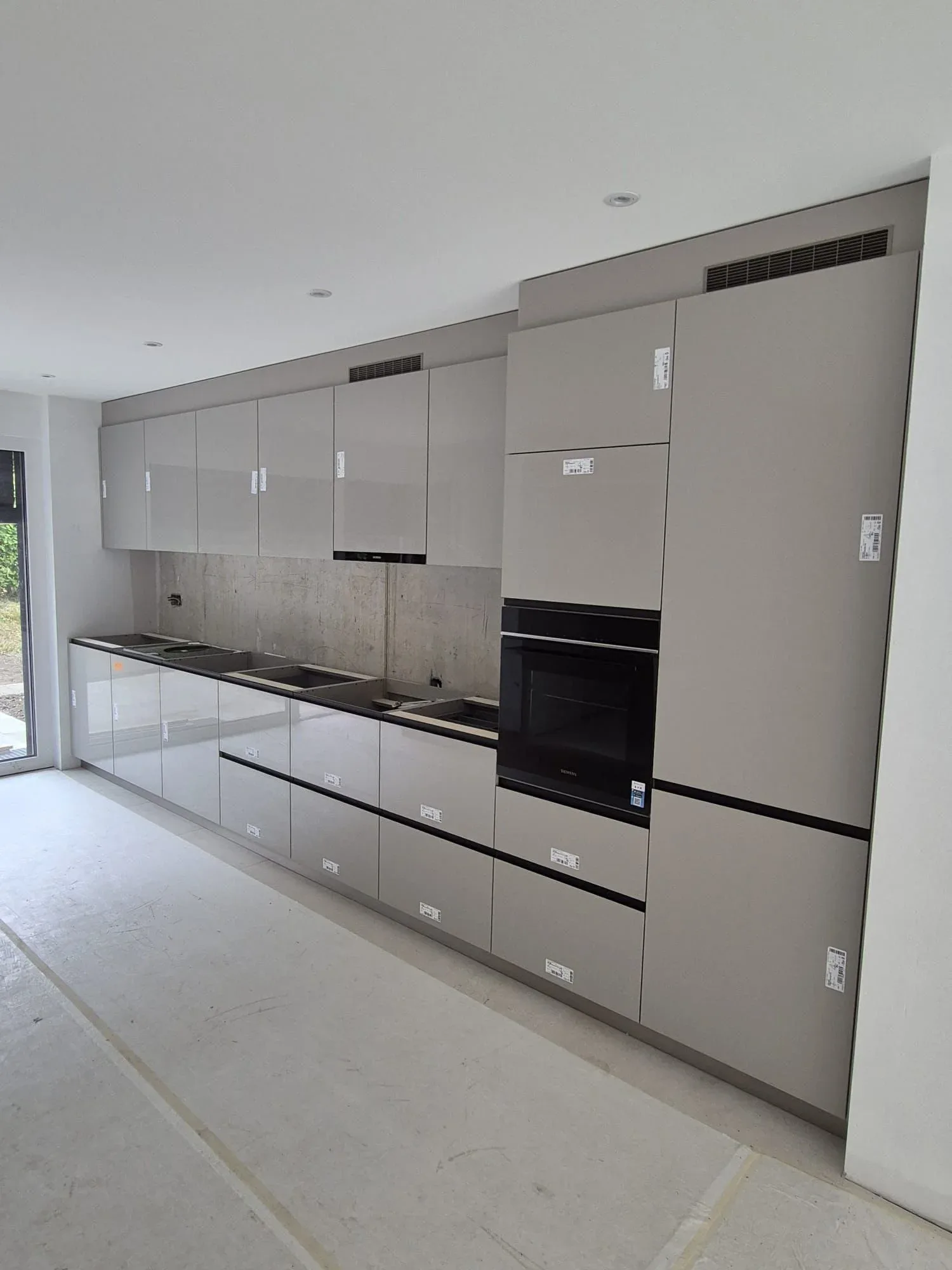 Cuisine linéaire gris clair laqué avec four Siemens, fraîchement posée en construction neuve