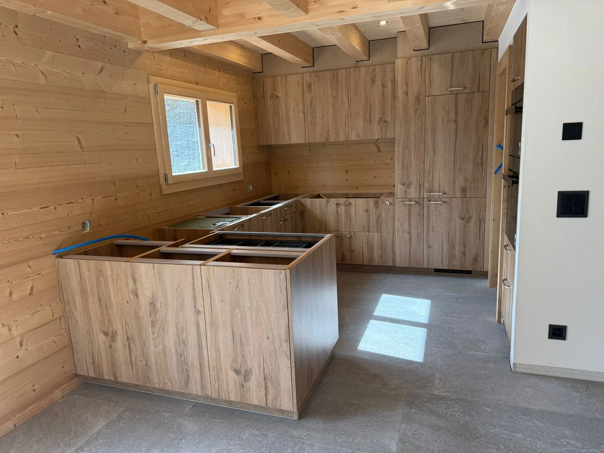 Cuisine de chalet en chêne avec îlot, murs et plafond en bois, en cours d'installation